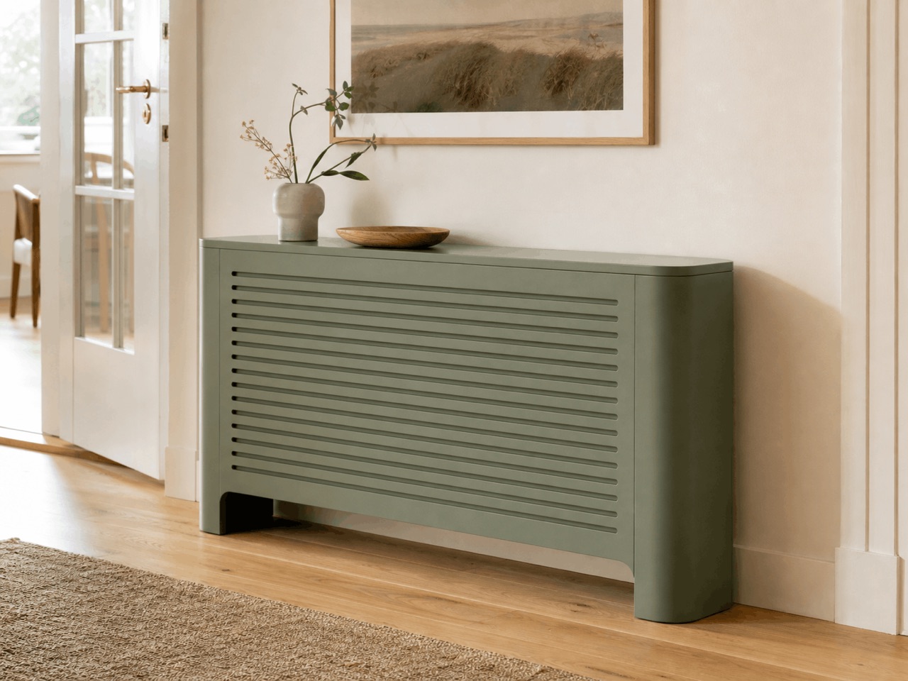 Grøn radiatorskjuler med vandrette åbninger ved en lys væg